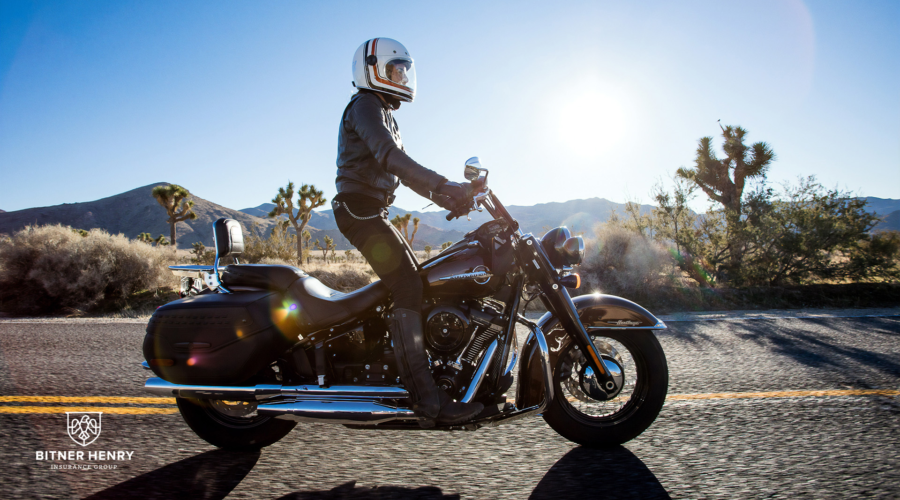 A motorcycle drives in the summer down a road. The Bitner Henry logo is in the bottom left.