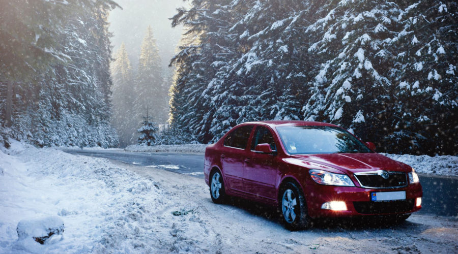 red car driving on snowy day