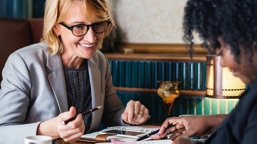 Saleswoman talking with woman at desk