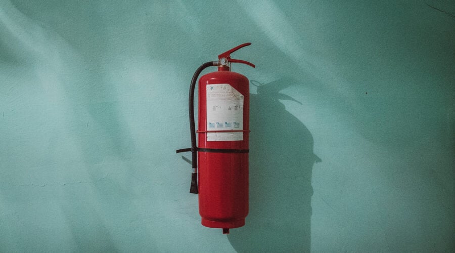 red fire extinguisher on green wall