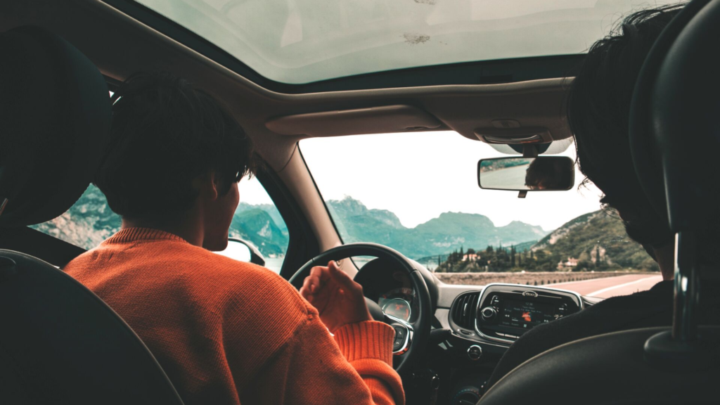 Person in orange sweater driving a car 