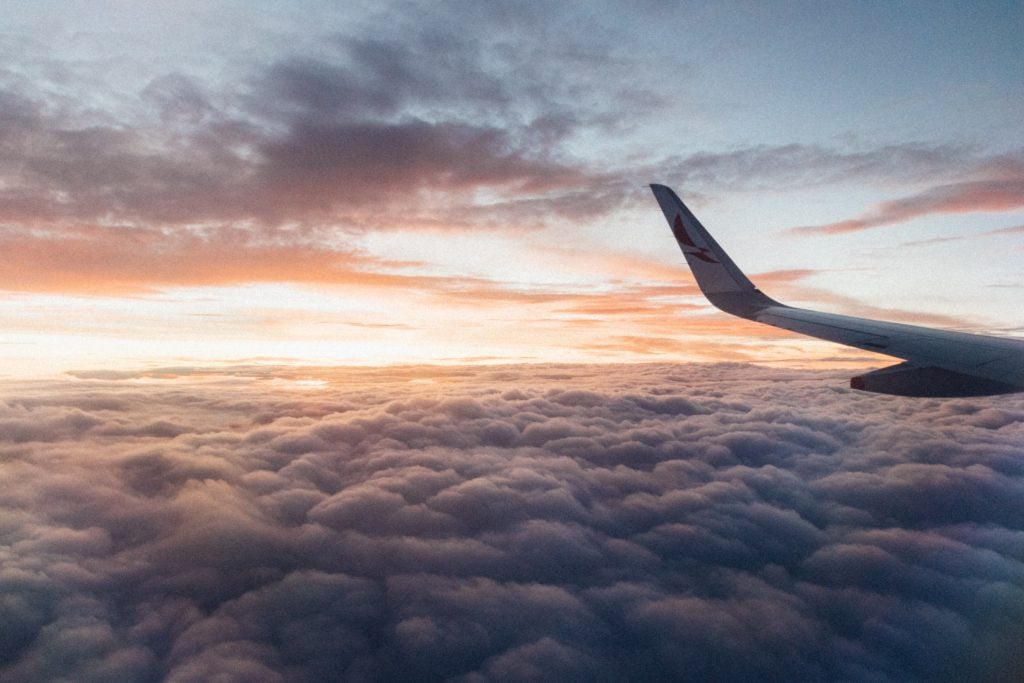 Airplane flying above the clouds at sunset