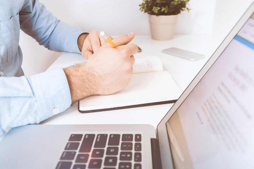 Person writing next to computer