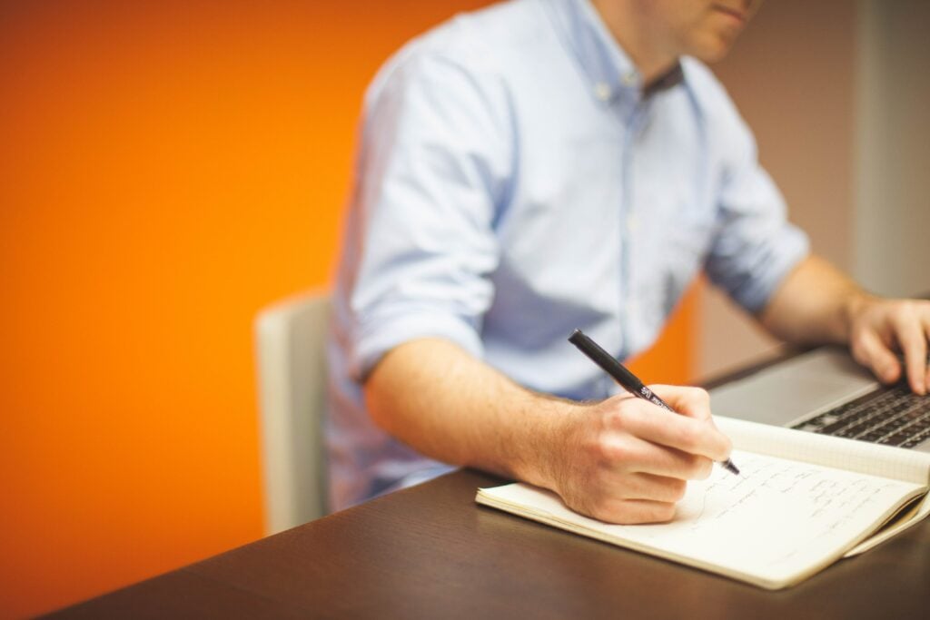 Man writing in a notebook at a desk