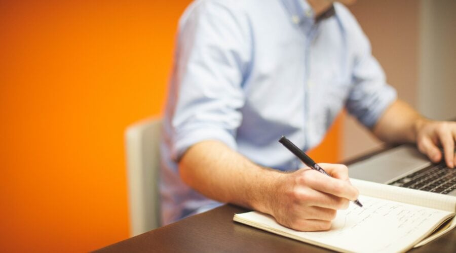 Man writing in a notebook at a desk