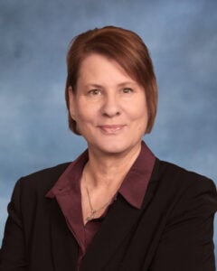 Linda Moran smiles at the camera from a blue background