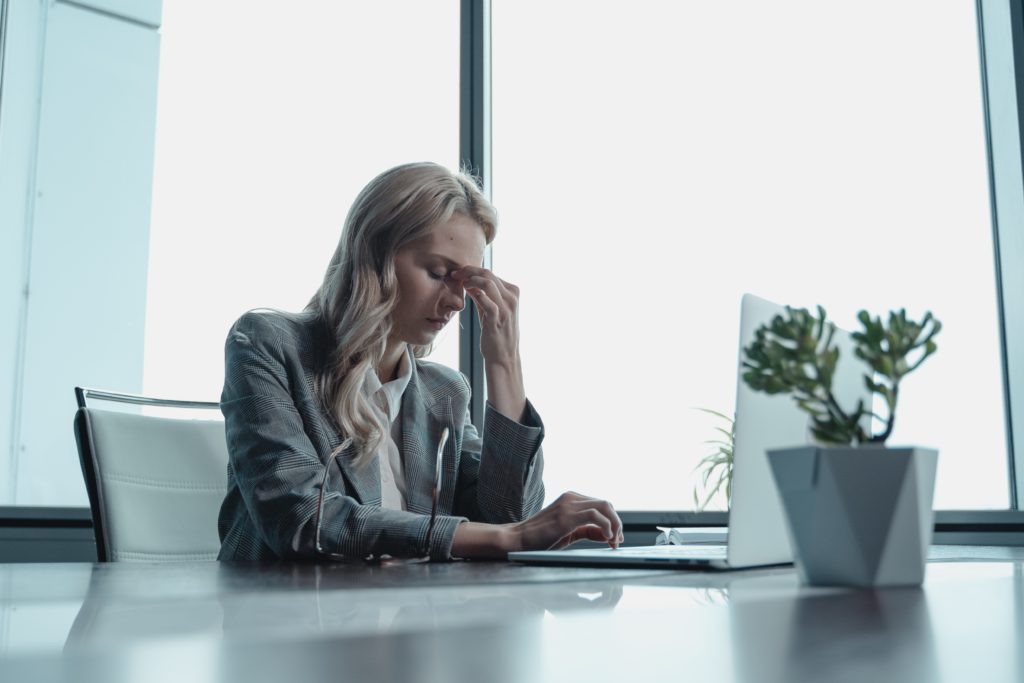 woman sitting in front of computer holding her head 