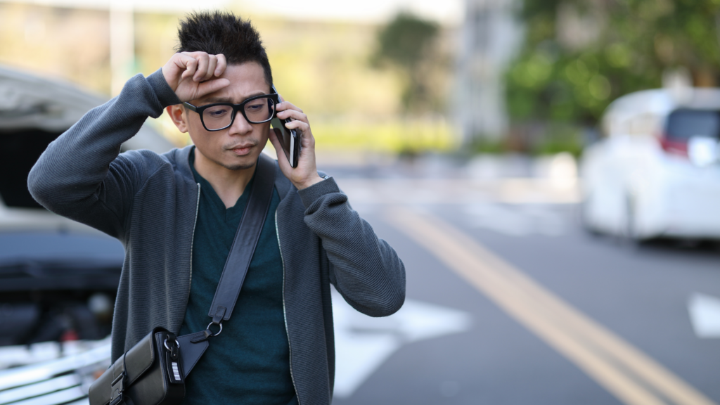 man on the phone looking stressed, standing in a parking lot