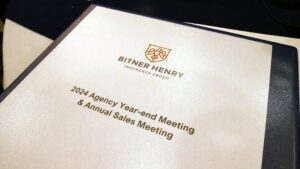 A dark blue binder that says, "2024 Agency Year-End Meeting & Annual Sales Meeting" with the Bitner Henry logo