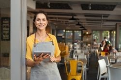 Small Business Owner A woman stands outside of her small business with a smile