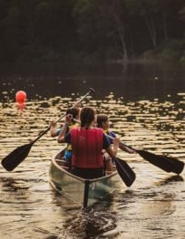 a camp counselor and camper canoe through a lake