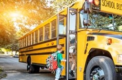 school bus A child boards a yellow school bus