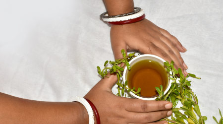 two hands hold a pot of healing tea with herbs