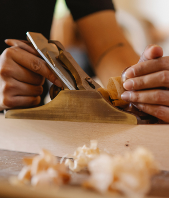 School Bus (3) A carpenter carefully crafts a shape, wood shavings in front of them
