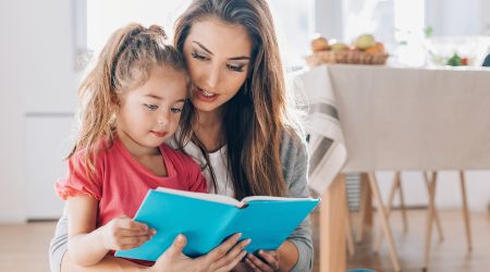 Teacher with Student A mom reads to her daughter as they homeschool from curriculum