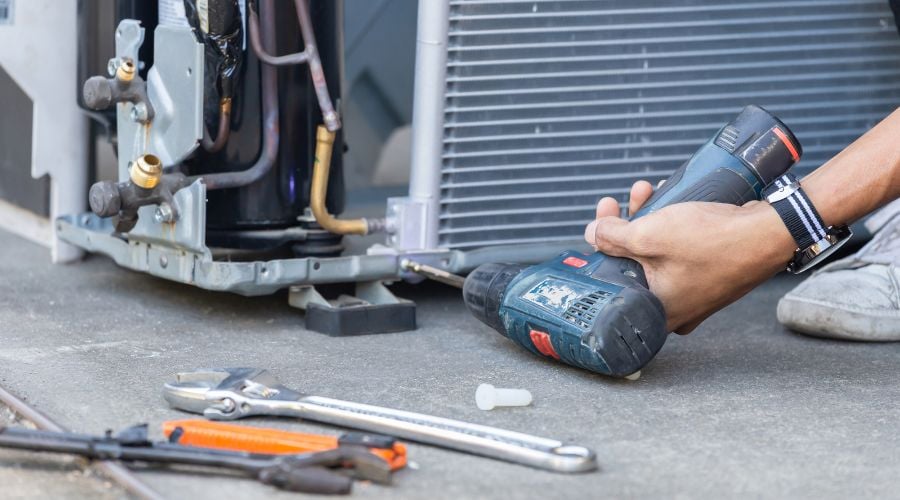 An HVAC Contractor installs an HVAC unit with a drill
