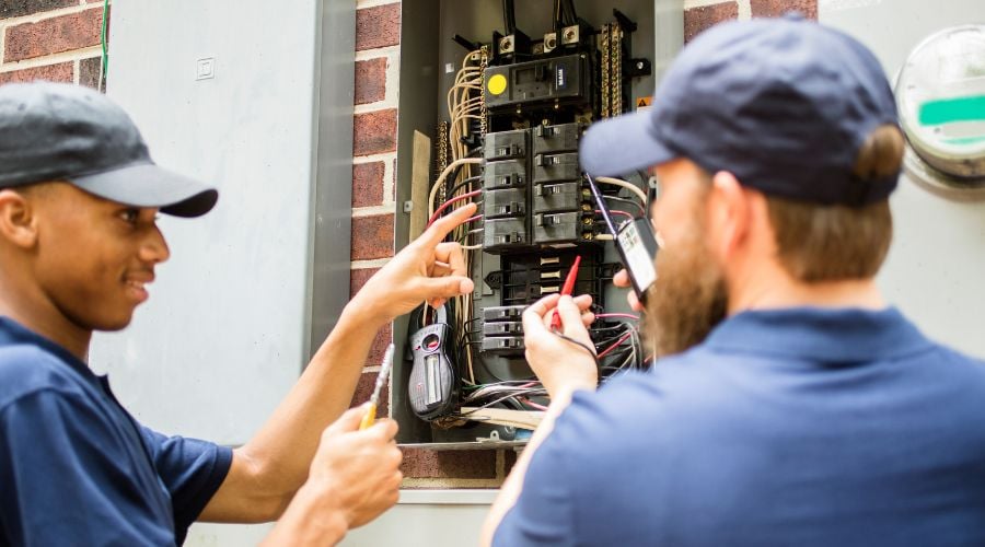 Two electricians work at a circuit box