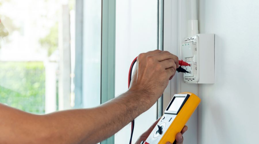 An electrician adjusts a light switch and the wires inside of it