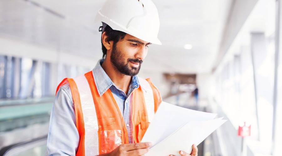 A contractor in a safety vest reviews contracts