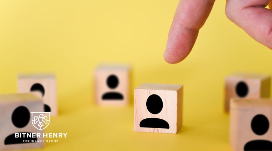 Someone makes a choice between many deductibles (represented by wooden blocks). The Bitner-Henry logo is in the bottom-left corner.