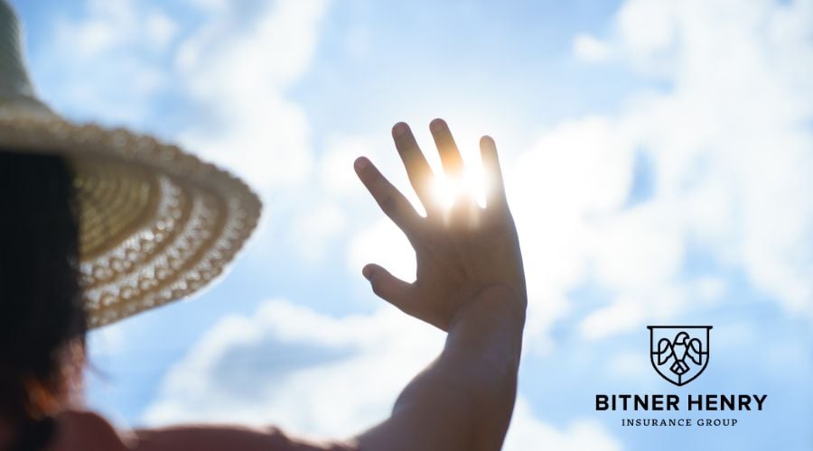 A person holds a hand up to the hot sun. The bitner-henry logo is in the bottom-right