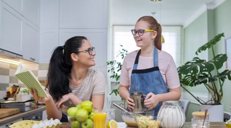 Two people- a recovery patient and a helper- cook together in the kitchen.