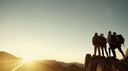 A group of intensive outpatient recovery patients celebrate recovery by watching the sun from a mountain