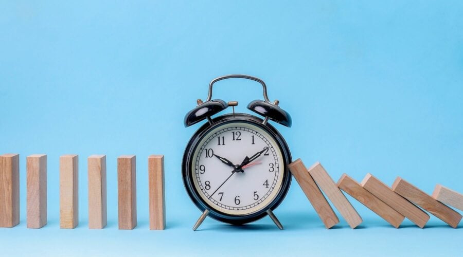 an alarm clock stops a line of cascading dominoes