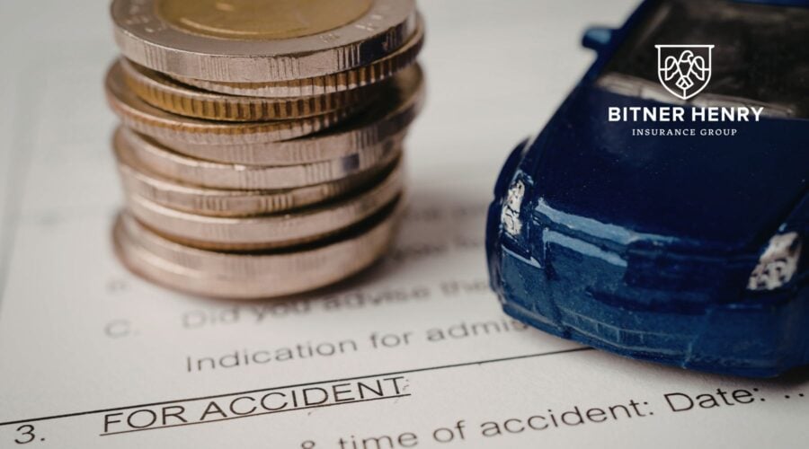 A car and a stack of money sit on liability papers with the bitner henry logo in the top right