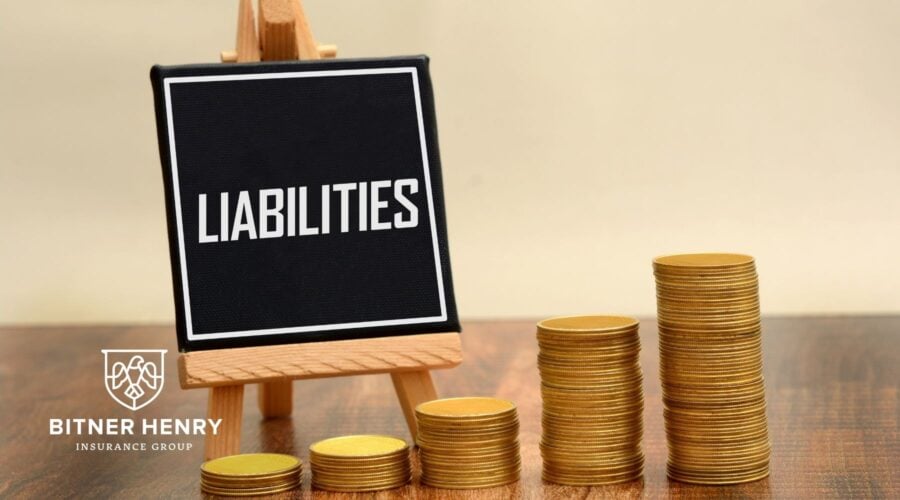 An easel with "liabilities" written on it, next to a stack of coins. The Bitner Henry logo is on the bottom left.