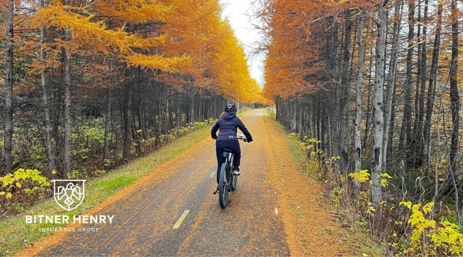 Someone rides an e-bike from their recovery program down a street. The Bitner Henry logo is in the bottom right.