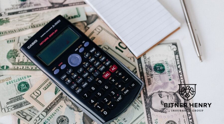 a calculator on top of cash to calculate the cost of recovery program auto claims. The Bitner Henry logo is in the bottom right.
