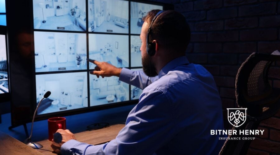 A man points at a security camera in a church security hub. The Bitner Henry logo is in the bottom right.