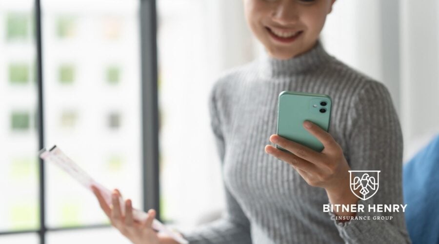 Someone checks a resume and her phone for the ministry background check for a church volunteer. She smiles. The Bitner Henry logo is in the bottom-right!