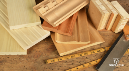 A group of pieces of wood next to a saw and a tape measurer