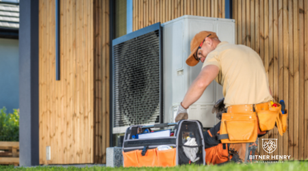 An HVAC worker fixes a heating unit with a toolbox. The Bitner Henry logo is in the bottom-right.