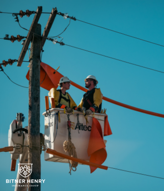 Electricians sit in a cherry picker while working on power lines