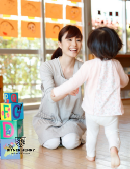 A woman smiles as a child runs towards her
