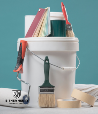 A painter's paint bucket with some tools in it.