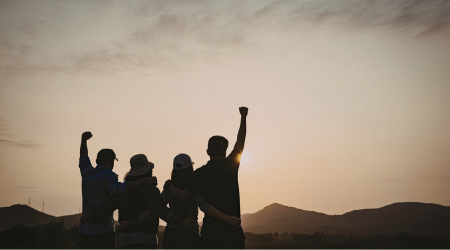 A united group of friends stands together and celebrates their church insurance success.