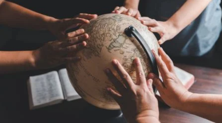 Everyone in the mission places their hands to pray for the globe. The Bitner Henry logo is in the bottom left.