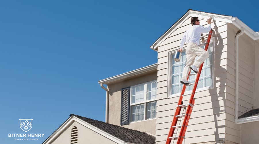 A man paints a house with a stepladder